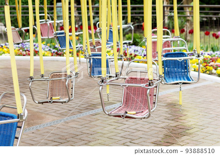 Empty hanging seats of a children's carousel in an amusement park. Selective focus. 93888510