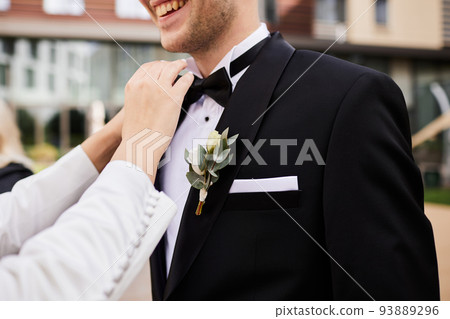 The bride corrects the groom's black tie from a tuxedo The bride corrects the groom's black tie from a tuxedo 93889296