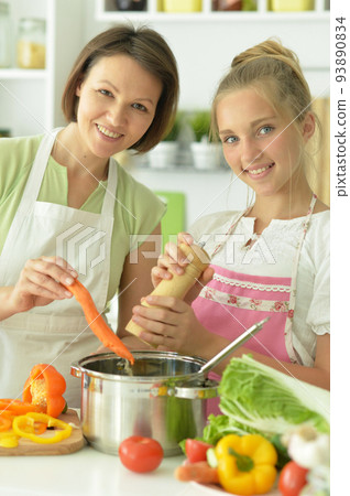 Girl with her mother cooking together at kitchen 93890834