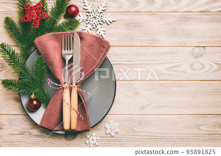Christmas table place setting with christmas decor and plates, kine, fork and spoon. Christmas holiday background. Top view with copy space Christmas table place setting with christmas decor and plates, kine, fork and spoon. Christmas holiday background. Top view with copy space 93891825