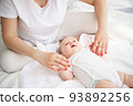 Family, motherhood, parenting, people and child care concept. Happy mother holding hands with adorable baby. 93892256