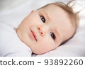 Portrait of a six-month-old baby girl, who lies on her back in her crib. 93892260