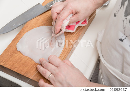 [A middle-aged housewife prepares a squid and peels the body with a cloth] 93892687