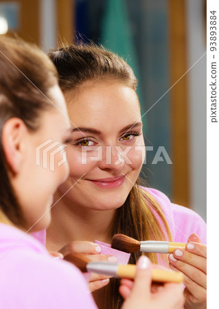 Woman applying bronzing powder with brush to her skin Woman applying bronzing powder with brush to her skin 93893884