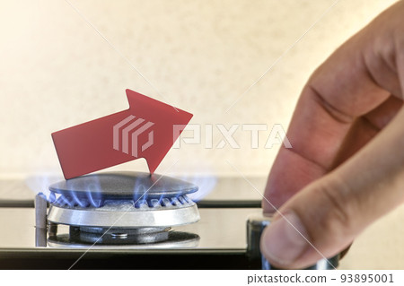 Gas price. Supply chains and the energy gas crisis. Gas stove with a burning flame and a graph arrow pointing up. Man's hand adjusts the gas supply Gas price. Supply chains and the energy gas crisis. Gas stove with a burning flame and a graph arrow pointing up. Man's hand adjusts the gas supply 93895001