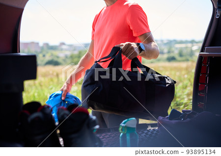 Sportsman getting bag out of trunk outdoors 93895134
