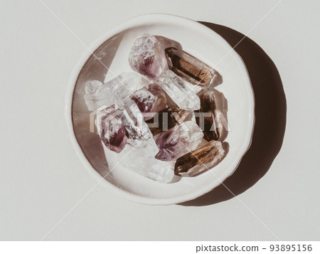 Light and grey crystals set on white plate on grey background 93895156