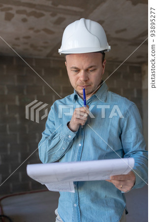 engineer in a white helmet with a project in his hands is thoughtful and professional. engineer in a white helmet with a project in his hands is thoughtful and professional. 93895277