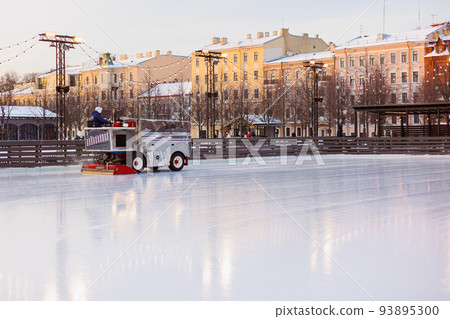 Skating rink for figure skating and outdoor recreation. The machine cleans the ice on the slide before the opening of the skating season Skating rink for figure skating and outdoor recreation. The machine cleans the ice on the slide before the opening of the skating season 93895300