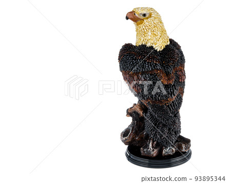 Figurine, statuette an eagle, hawk, falcon on stand on white background. Wild bird sculpture inlaid with natural amber stones. Use for interior design. 93895344
