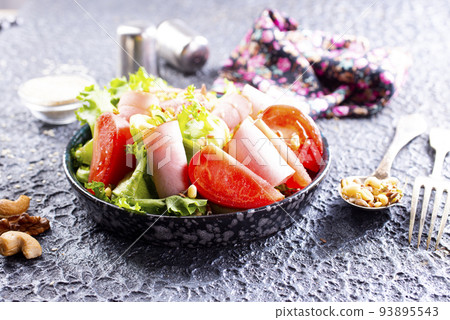 Fresh vegetable salad with slices of ham , cherry tomatoes lettuce leaves. Ham salad. Take away food. 93895543