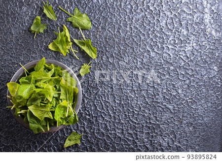 Fresh baby spinach leaves in bowl on dark background 93895824