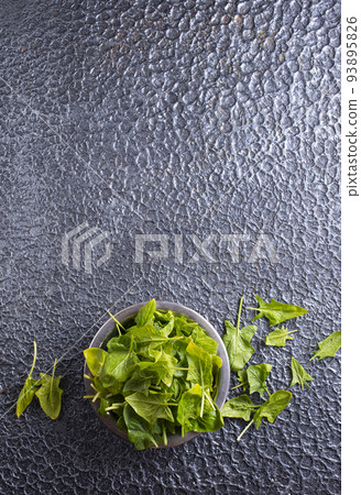 Fresh baby spinach leaves in bowl on dark background 93895826