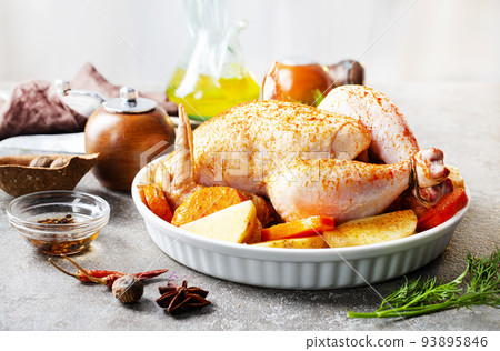 Raw chicken marinated in sour cream sauce with vegetables is in a white tray. 93895846