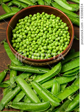 green sweet peas on a dark wooden background, still life, concept of fresh and healthy food green sweet peas on a dark wooden background, still life, concept of fresh and healthy food 93896654