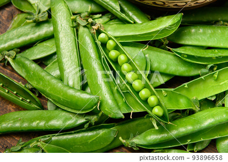 green sweet peas on a dark wooden background, still life, concept of fresh and healthy food green sweet peas on a dark wooden background, still life, concept of fresh and healthy food 93896658