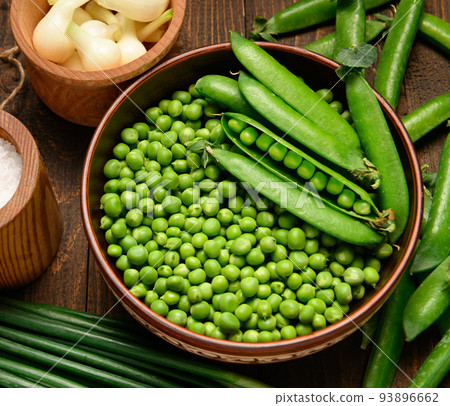 green sweet peas on a dark wooden background, onion, salt, still life, concept of fresh and healthy food green sweet peas on a dark wooden background, onion, salt, still life, concept of fresh and healthy food 93896662