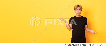 Portrait of confused and annoyed asian guy spread hands sideways, cant understand something, standing yellow background Portrait of confused and annoyed asian guy spread hands sideways, cant understand something, standing yellow background 93897122