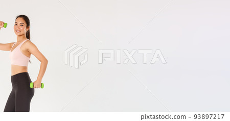 Sport, gym and healthy body concept. Full length of smiling female athlete, cute girl doing fitness exercises with dumbbells. Sportswoman in active wear workout in gym, white background 93897217