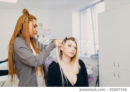 Hairstylist braided afro braids dreadlocks kanekalon pigtails hair of female client in barber salon. 93897348