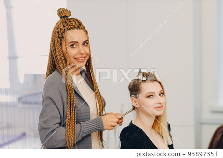 Hairstylist braided afro braids dreadlocks kanekalon pigtails hair of female client in barber salon. Hairstylist braided afro braids dreadlocks kanekalon pigtails hair of female client in barber salon. 93897351
