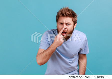 You are liar. Portrait of shocked bearded man standing, touching his nose and showing lie gesture, suspecting falsehood, dishonest talk. Indoor studio shot isolated on blue background. You are liar. Portrait of shocked bearded man standing, touching his nose and showing lie gesture, suspecting falsehood, dishonest talk. Indoor studio shot isolated on blue background. 93898156