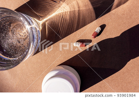 Pills and glass of water on brown background. Medicine, healthcare concept Pills and glass of water on brown background. Medicine, healthcare concept 93901984