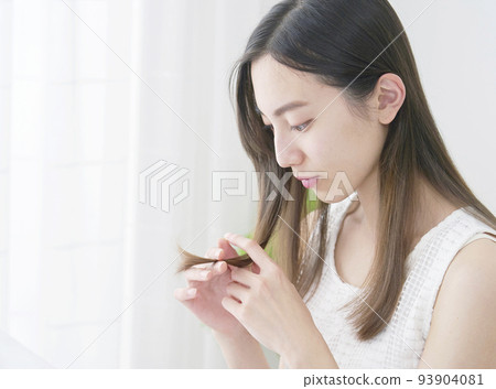 A woman looking at her hair in the living room A woman looking at her hair in the living room 93904081