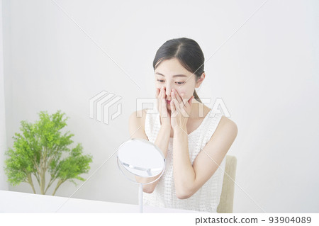 A woman doing facial skin care in the living room 93904089