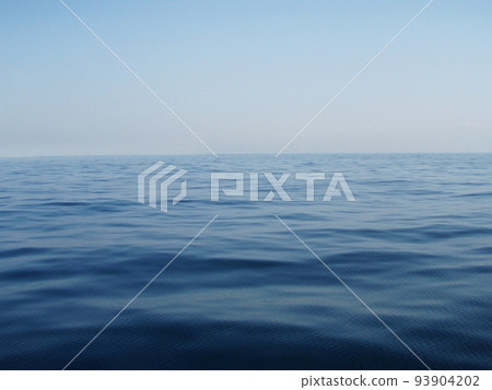 A background image taken from a calm ocean with a faint sunrise toward the horizon. 93904202