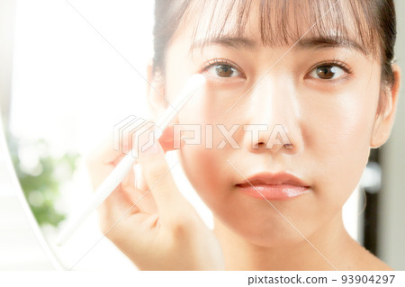 Young woman doing eye makeup while looking in the mirror beauty image 93904297