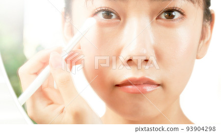 年輕女子一邊看著鏡子美容形像一邊做眼妝 93904298