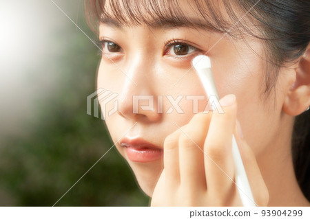 年輕女子一邊看著鏡子美容形像一邊做眼妝 年輕女子一邊看著鏡子美容形像一邊做眼妝 93904299