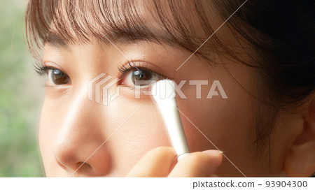 年輕女子一邊看著鏡子美容形像一邊做眼妝 93904300