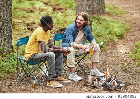 Guys sitting near the fire outdoors 93904882
