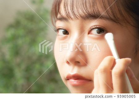 年輕女子一邊看著鏡子美容形像一邊做眼妝 93905005