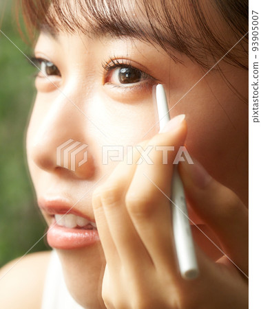 年輕女子一邊看著鏡子美容形像一邊做眼妝 93905007