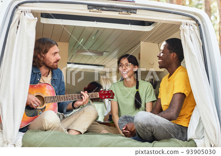 Young people playing guitar in motorhome 93905030