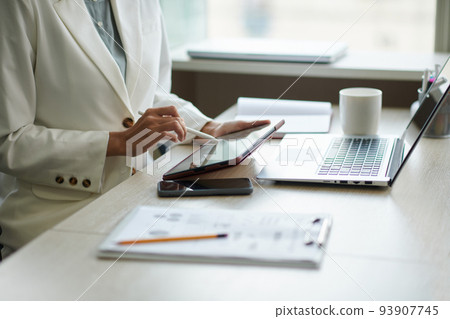 Close-up image of businesswoman checking documents and reports on tablet computer 93907745