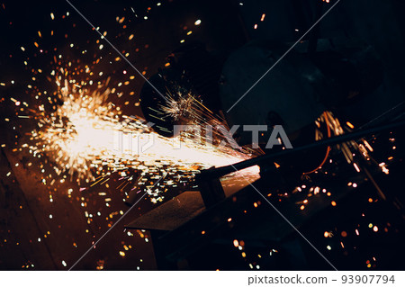 Metal processing with big compound mitre saw with circular blade. Sparks in metalworking at factory Metal processing with big compound mitre saw with circular blade. Sparks in metalworking at factory 93907794