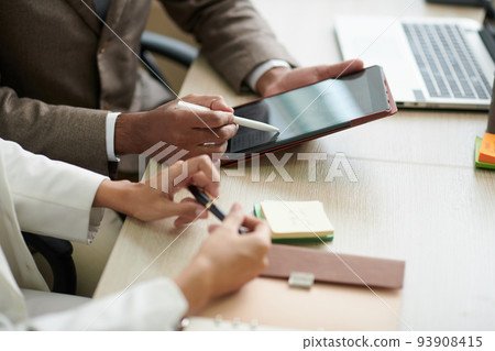 Hands of business people discussing article on upcoming recession on tablet computer Hands of business people discussing article on upcoming recession on tablet computer 93908415