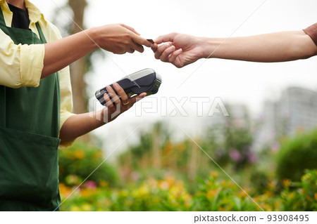 Customer giving credit card to flower nursery worker to pay for order Customer giving credit card to flower nursery worker to pay for order 93908495