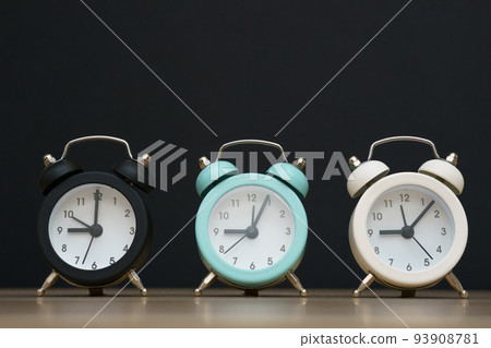 Three small alarm clocks black blue and white show nine o'clock, stand 93908781