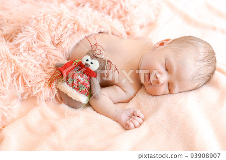 Closeup portrait, newborn baby with owl toy lying on bed, napping or sleeping Closeup portrait, newborn baby with owl toy lying on bed, napping or sleeping 93908907