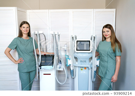 Two women specialists in hardware cosmetology stand in massage room at laser Two women specialists in hardware cosmetology stand in massage room at laser 93909214