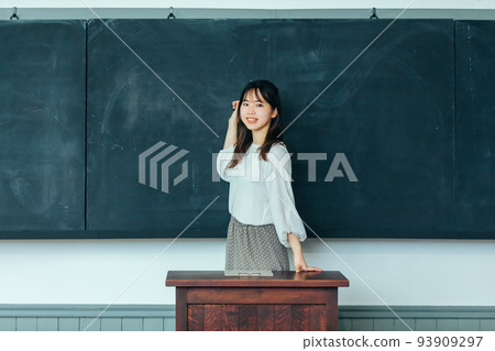 A smiling woman in front of a blackboard blackboard 93909297