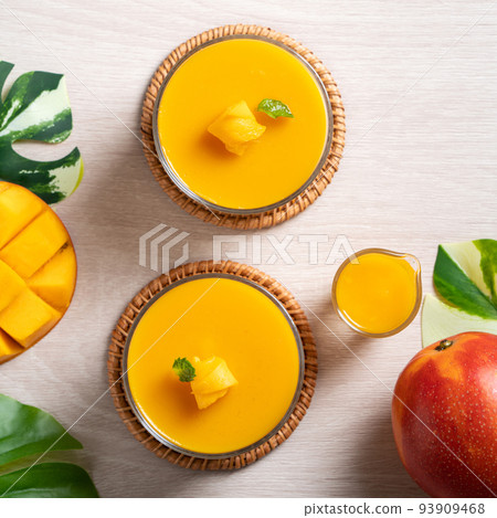 Delicious mango panna cotta mousse pudding on white table background. Delicious mango panna cotta mousse pudding on white table background. 93909468