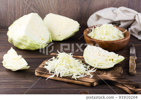 Fresh raw cabbage cut into strips on a cutting board on a wooden table. Vegetarian diet 93910204