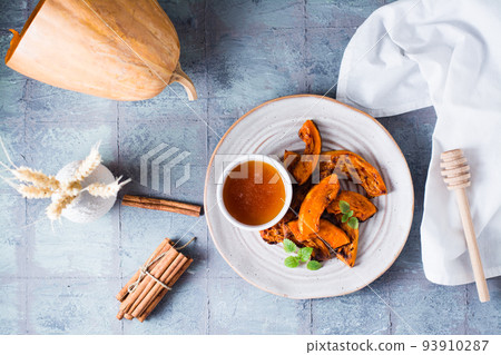 Baked pumpkin slices, honey and mint leaves on a plate on the table. Vegetarian food. Thanksgiving Day. Top view Baked pumpkin slices, honey and mint leaves on a plate on the table. Vegetarian food. Thanksgiving Day. Top view 93910287