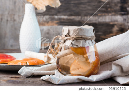 Pickled fly agarics in a jar on a wooden table. Microdosing and Alternative Medicine. 93910523